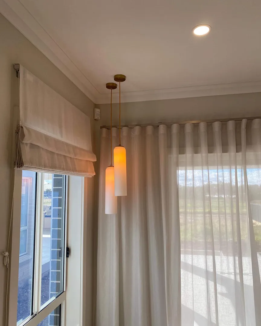 Modern hanging lights near a window with curtains.