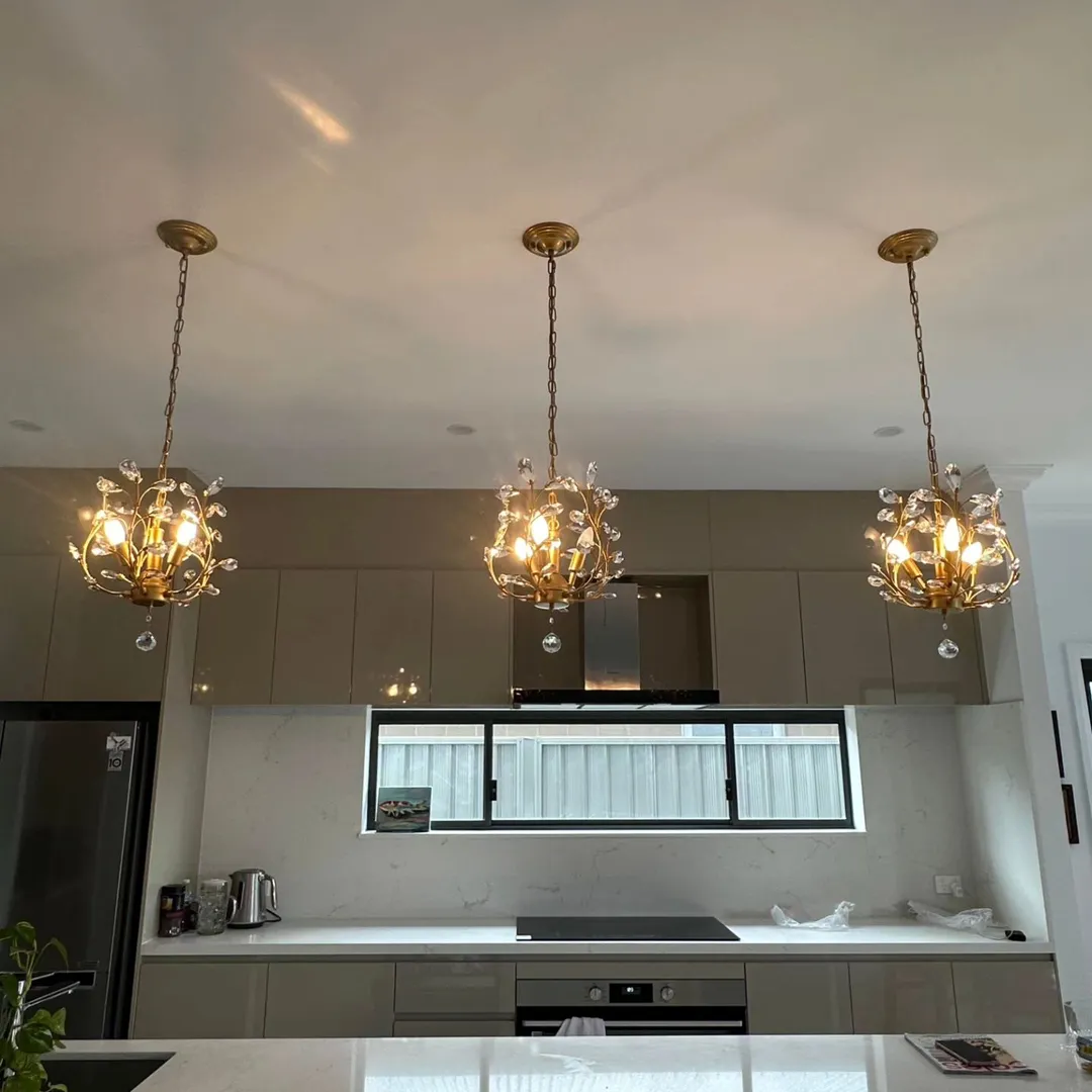 Modern kitchen with three hanging chandeliers.