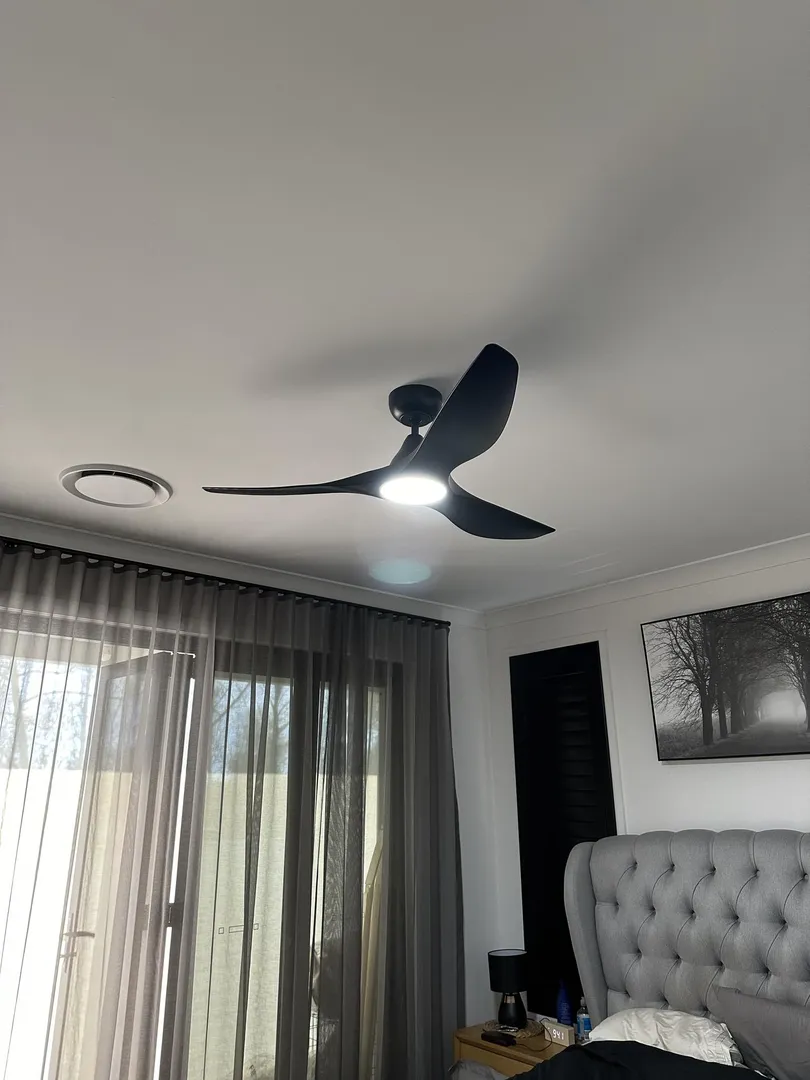 Modern bedroom with ceiling fan and wall art.